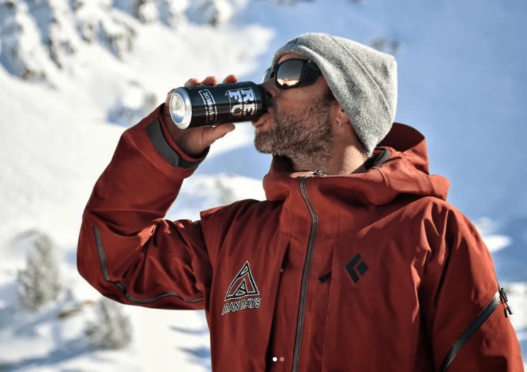 Un instructor de Aran Days bebiendo una cerveza REFU en la nieve