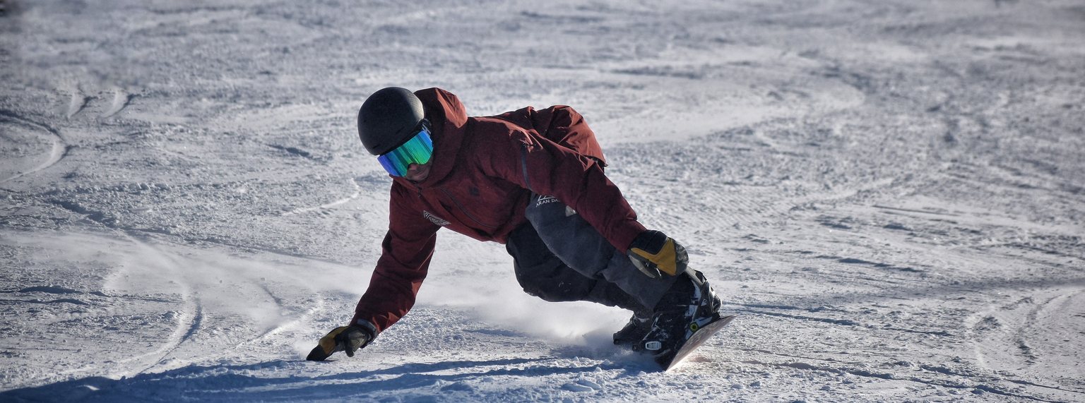 Snowboarder deslizándose por una pista de Baqueira Beret con una chaqueta de Aran Days