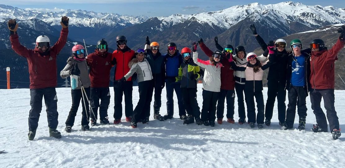 Grupo de esquiadores con los brazos en alto celebrando en lo alto de una pista de Baqueira Beret