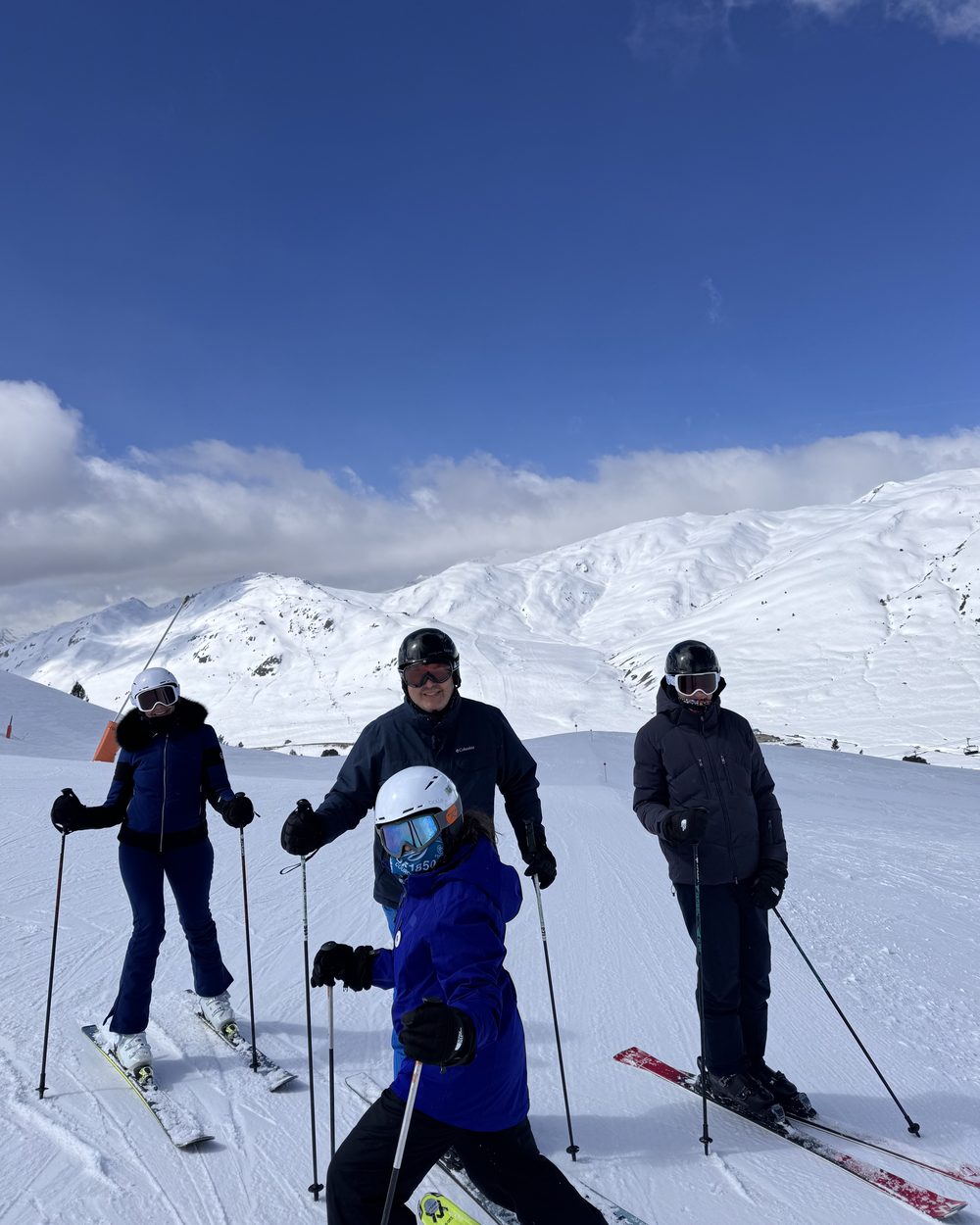 Familia posando con esquís en una pista de Baqueira Beret con montañas nevadas al fondo