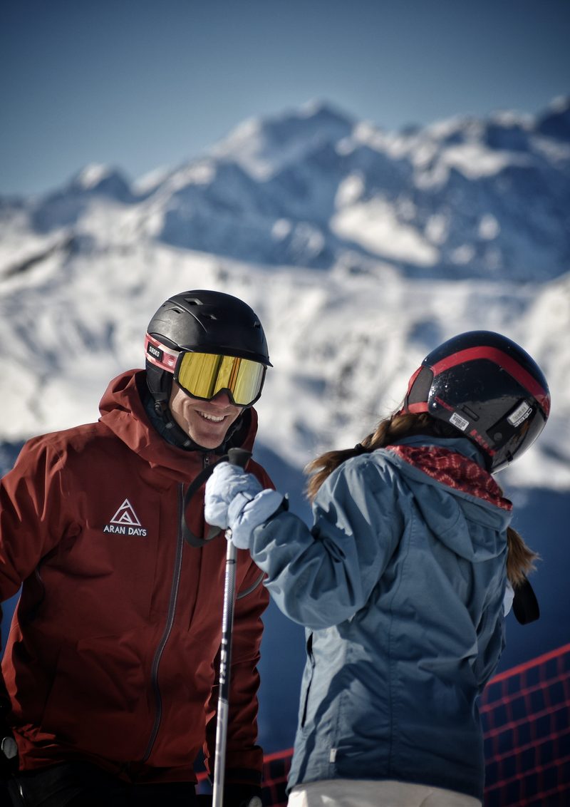 Instructor de Aran Days conversando con una alumna con las montañas nevadas al fondo