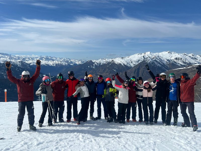 Grupo de esquiadores celebrando con los brazos en alto sobre la nieve